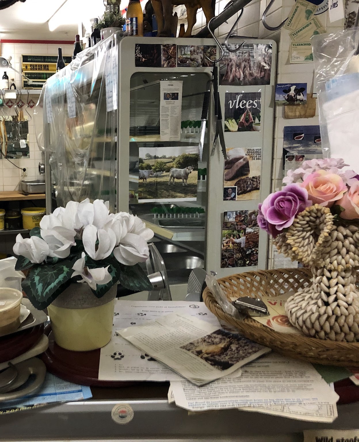 De toonbank met bloemen, de vitrine en de knipsels en recepten die op de kast geprikt zijn