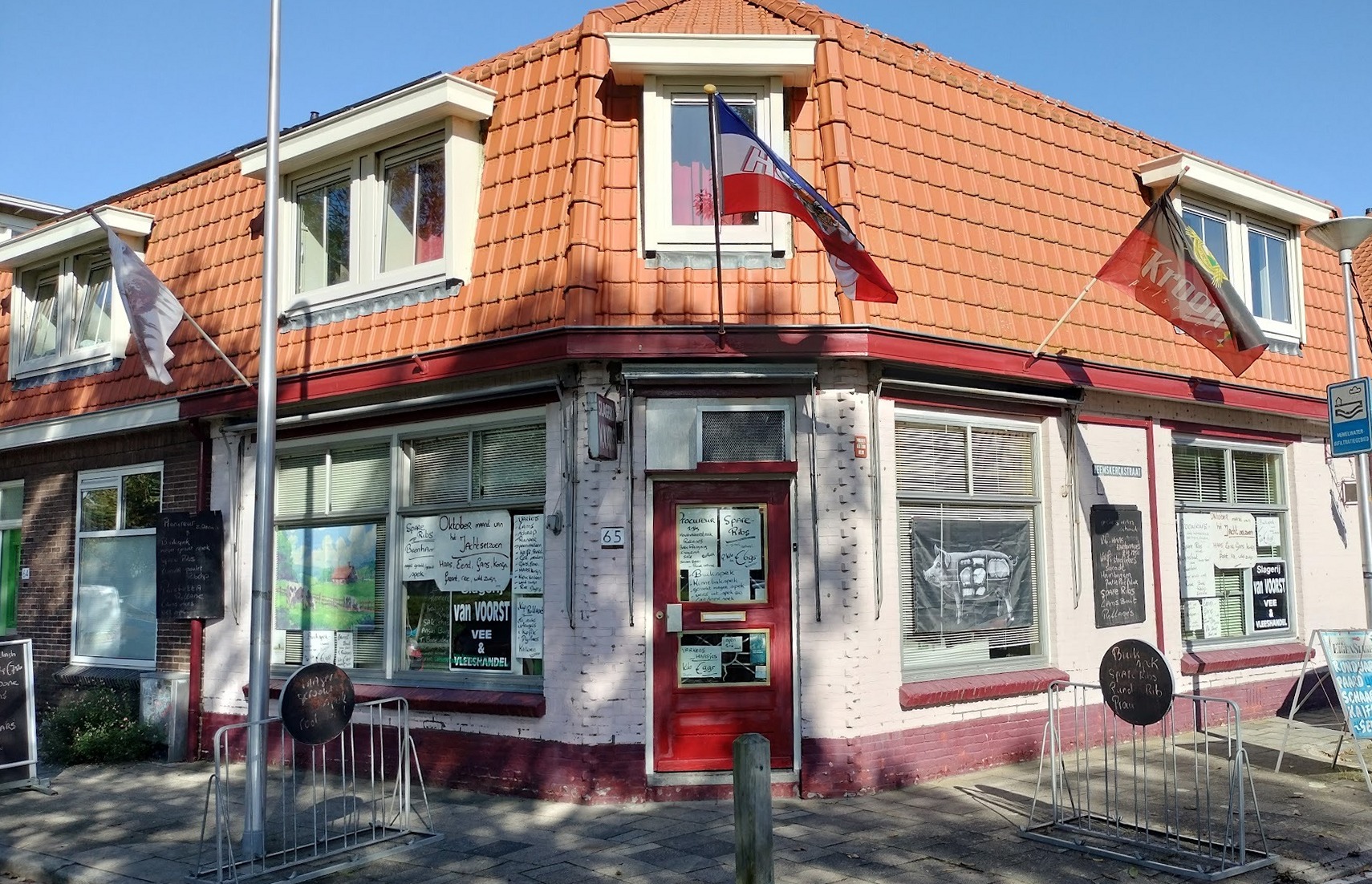 De hoekwinkel van Slagerij W. van Voorst aan de Evertsenstraat in Zwolle, met de rode deur en de handgeschreven bordjes in de etalage